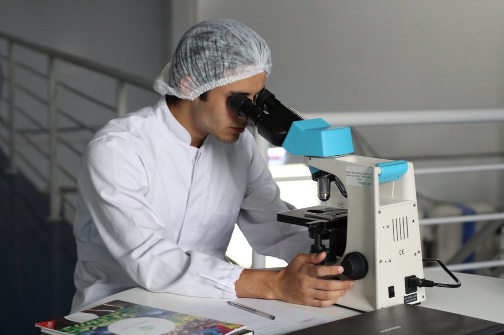 man looking into a microscope - do the necessary research